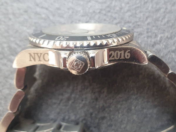 Close-up of a watch with 'NYC' and '2016' engraving